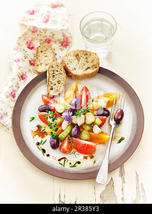 Lacto fermentierte Tomaten, Gurken und Oliven, serviert mit Kräutern und Knoblauchbrot Stockfoto