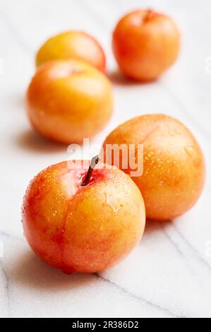 Gelbe Pflaumen auf einer weißen Marmorplatte Stockfoto