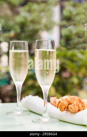 Zwei Gläser Prosecco auf einem Tisch draußen mit großen Käsehäppchen Stockfoto