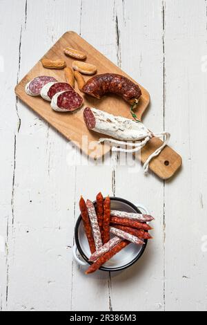 Verschiedene Spanische Wurst in einem Emaille Schüssel und auf einem Holzbrett (Ansicht von oben) Stockfoto