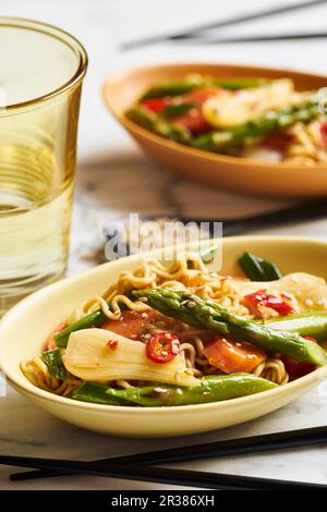 Asiatische Nudeln mit grünem Spargel, Frühlingszwiebeln, Karotten, rotem Paprika und Sesamsamen Stockfoto