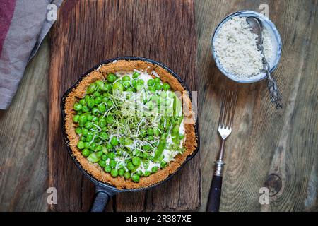 Eine mehlfreie Frühlingstorte mit gedämpftem Spargel, Erbsen, Ziegenkäse, Kresse und Parmesan Stockfoto