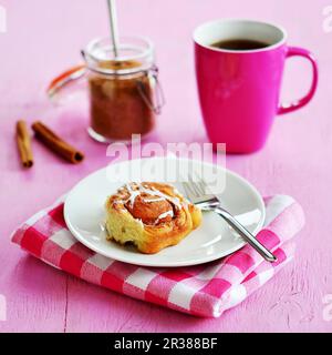 Eine Zimtschnecke serviert mit Tee Stockfoto