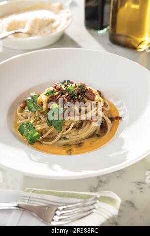 Spaghetti mit Chanterelles und schwarzem Trüffel über Butternusskürbis-Püree in weißer, breiter Schüssel Stockfoto