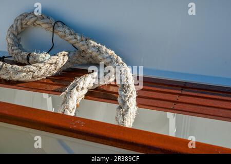 Altes verwittertes Seil, das auf der Seite des Boots liegt. Stockfoto