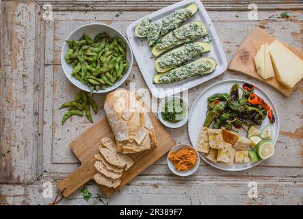 Verschiedene Vorspeisen: Edamame, gefüllte Zucchini, Pimientos, Brot und Käse Stockfoto