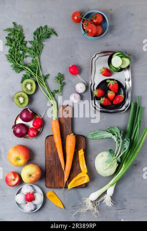 Eine Anordnung von Frühlingszwiebeln, Knoblauch, Äpfeln, Tomaten, Paprika, Karotten, Kiwis, Radieschen, Erdbeeren und Kohlrabi Stockfoto