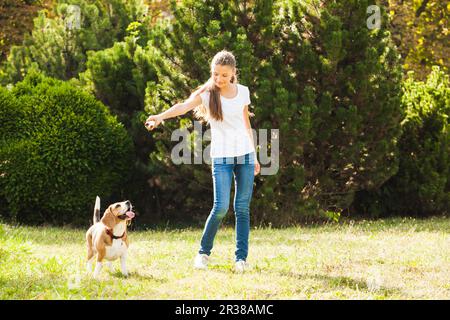 Mädchen spielt mit einem Hund auf dem Hof Stockfoto