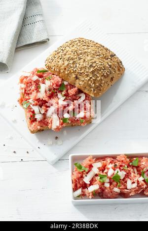 Ein knuspriges Brötchen, garniert mit gemahlenem Schweinebraten und Zwiebeln Stockfoto