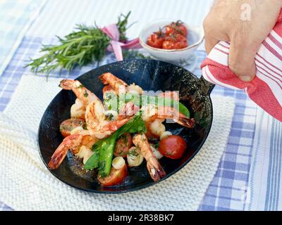 Garnelen in einem Topf mit Zuckererbsen und Kirschtomaten Stockfoto