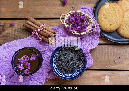 Grüner Tee mit Zimtstangen, essbaren Blumen und Keksen Stockfoto