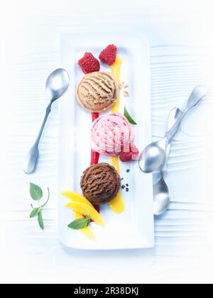 Verschiedene Eislöffel mit Mango- und Himbeersauce Stockfoto