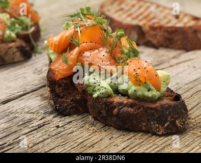 Gegrilltes Brot mit Avocado, geräuchertem Lachs und Kräutern Stockfoto