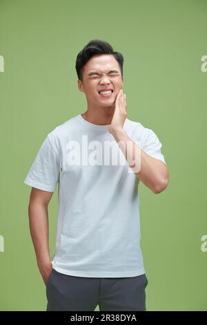 Ein Mann fühlt Zahnschmerzen mit grünem Hintergrund, asiatisch Stockfoto