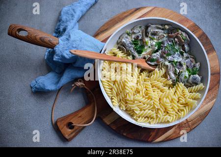 Pasta mit Pilzen in einer cremigen Sauce, serviert in einer Pfanne (von oben gesehen) Stockfoto