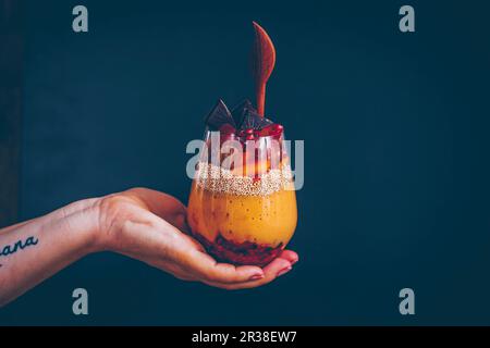 Eine Hand, die ein Glas Parfait hält Stockfoto