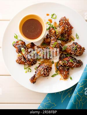 Gegrillter Honig und Sesamsamen Hähnchenflügel auf einem weißen Holztisch Stockfoto