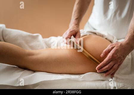 Unbekannte weiße Frau, die eine madero-Therapie-Massage gegen Cellulite-Behandlung durch einen professionellen Therapeuten mit Holzwerkzeugen in den Händen im Studio oder in der sa erhalten hat Stockfoto