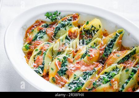 Schalenpasta mit Spinat-Ricotta-Füllung in Tomatensauce mit Parmesan Stockfoto