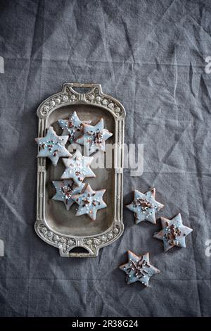Sternförmige vegane Kekse mit hellblauer Pudervereisung und Zuckerperlen Stockfoto