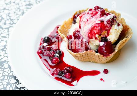 Vanilleeis mit Beerensauce in einer Waffelschüssel Stockfoto