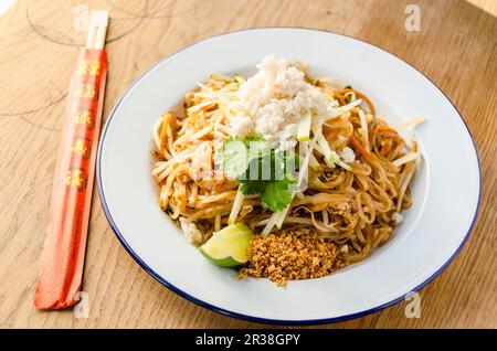 Pad thai Rührnudeln mit Garnelen, Chili, Bohnen, Sprossen, Frühlingszwiebeln, Karotten, Krabbenfleisch, Apfel, Limette und Erdnuss Stockfoto