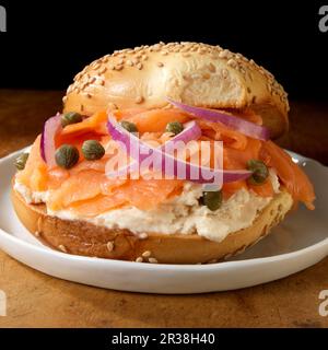 Lachs und Frischkäse auf Sesambagel mit Kapern und roten Zwiebeln Stockfoto