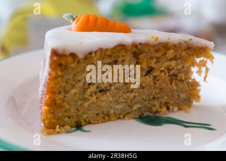 Eine Scheibe Karottenkuchen mit Sahnehäubchen und Marzipan-Karotten Stockfoto