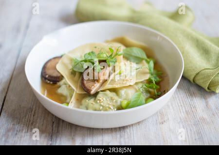 Knödel in Brühe mit Edamam, Pilzen und Brunnenkresse Stockfoto