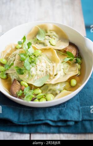 Knödel in Brühe mit Edamam, Pilzen und Brunnenkresse Stockfoto