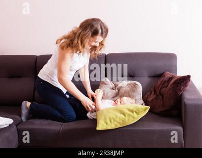 Mutter kitzeln Ihr Baby auf der Couch Stockfoto