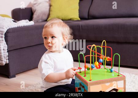 Kleinkind baby boy drinnen spielen mit Spielzeug sitzen auf weichen Teppich Stockfoto