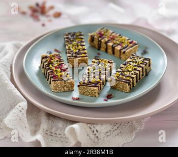 Vegane Amaranth- und Mandelriegel mit Schokolade, getrockneten Blumen, Pistazien und Hanfsamen Stockfoto