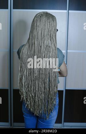 Viele dünne afrikanische Zöpfe mit künstlichem Material, blonde Nahaufnahme auf hellem Hintergrund, Schönheitsstudio Stockfoto