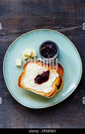 Blick von oben auf Toast mit Vollkornbrot mit Butter und Obstmarmelade für ein traditionelles Frühstück auf Holzhintergrund Stockfoto