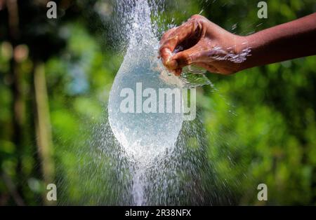 Wasser spritzt in Zeitlupe aus einem Ballon mit Handschlag Stockfoto