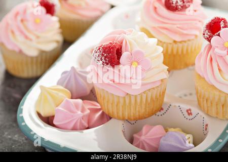 Vanille- und Himbeeren-Cupcakes mit Frischkäse-Zuckerguss Stockfoto