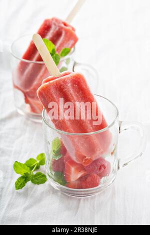 Erdbeereis Lollies serviert mit Beeren in Glasbechern Stockfoto