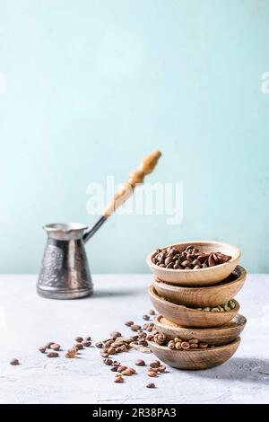 Verschiedene Kaffeebohnen und Gewürze in Holzschüsseln im Stapel über dem grauen Tisch Stockfoto