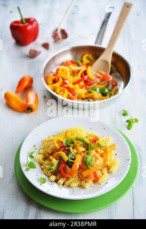 Spiralnudeln mit bunten Paprikastreifen und Basilikum Stockfoto