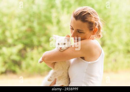 Frau streicheln Ihre reizende Katze im Sommer City Walk Stockfoto
