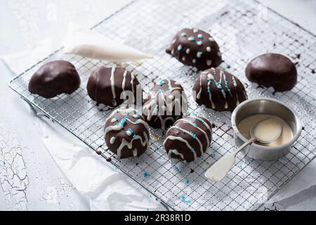 Dekorierte, eiförmige Kuchenpralinen mit Reismilchschokolade (vegan) Stockfoto