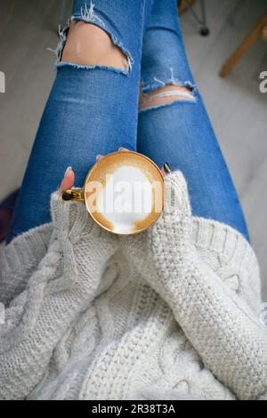 Eine Frau hält eine Tasse Kaffee in ihren Händen Stockfoto