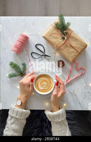 Eine Frau, die eine Tasse Kaffee in der Hand hält, einen Marmortisch und Kaffee Stockfoto