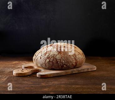 Ein Laib mit knusprigem Brot auf einem Holzbrett Stockfoto