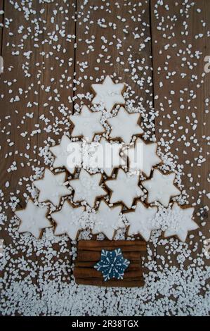 Ein Weihnachtsbaum aus Zimtsternen, Zuckernippchen und Zimtstangen mit Schneeflockenkeksen Stockfoto