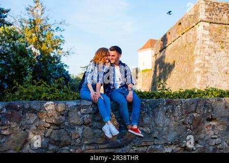 Romantisches Paar sitzt auf einer Wand in der Nähe der Burg Stockfoto