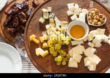 Käseplatte mit Haselnüssen, Honig, Trauben auf hölzernen Tisch Stockfoto