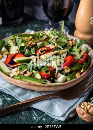 Salat mit roher Zucchini, Erdbeeren, Rucola, gewürfeltem Käse, Walnüssen und Balsamglasur Stockfoto