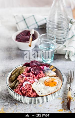 Lobscouse mit Hering, Spiegelei, Rote Bete und Gewürzgurken Stockfoto